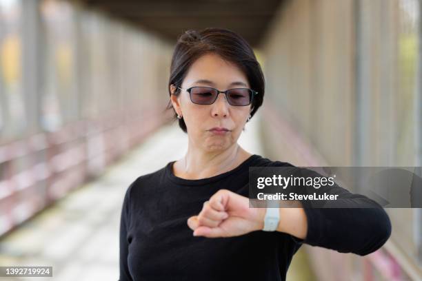 mulher irritada verificando a hora - tinted sunglasses - fotografias e filmes do acervo