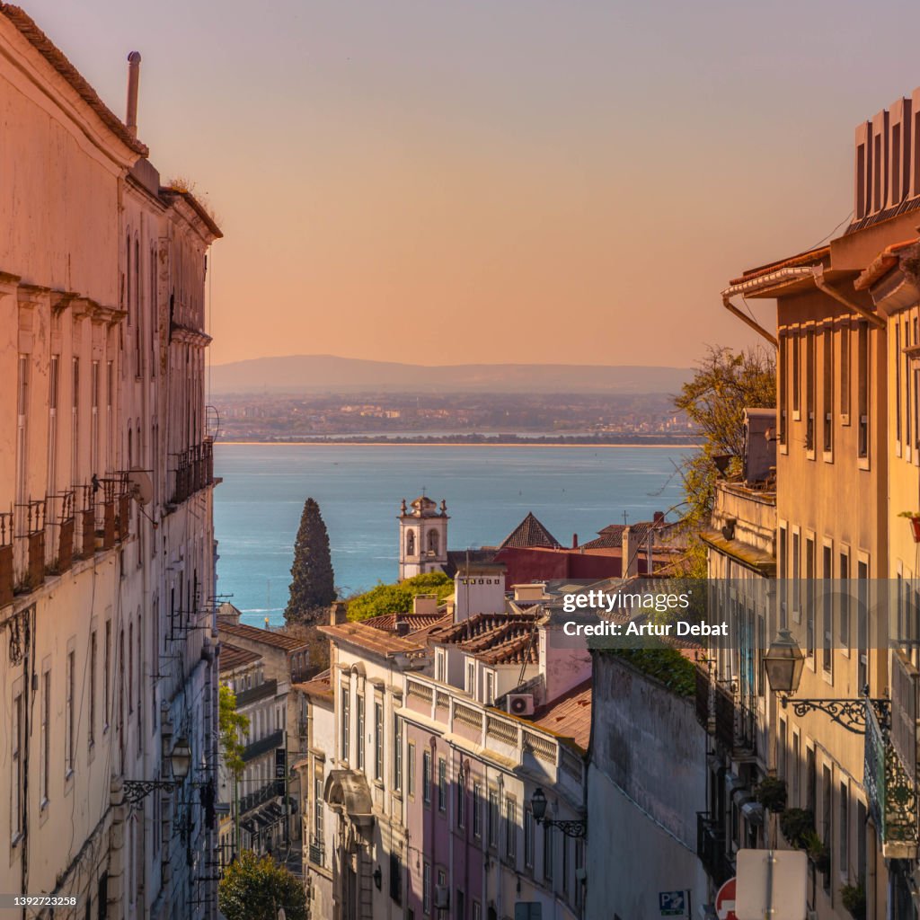 Colorful view of the Alfama district in Lisbon with church and sunset sky.
