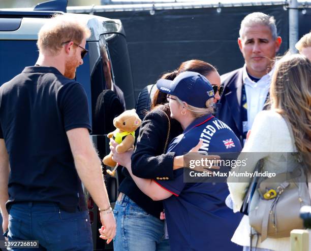Prince Harry, Duke of Sussex looks on as Meghan, Duchess of Sussex, accompanied by bodyguard Christopher Sanchez , hugs a competitor as they attend...