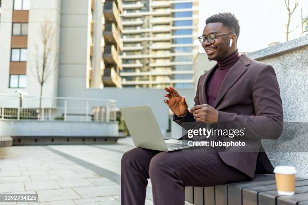 shot of a handsome young man waving while taking a video call on his laptop - radio controlled handset stock pictures, royalty-free photos & images