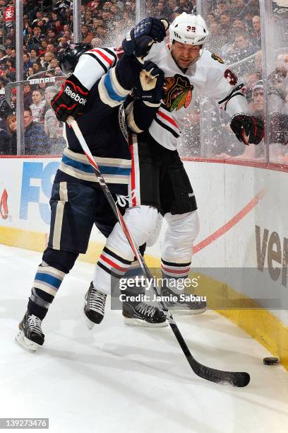 Mark Letestu of the Columbus Blue Jackets checks John Scott of the Chicago Blackhawks while battling for a loose puck during the first period on...