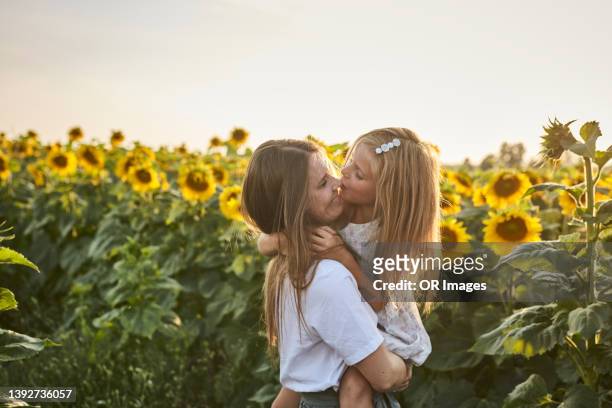 happy affectionate mother carrying daughter in a sunflower field - happy sunflower stock pictures, royalty-free photos & images