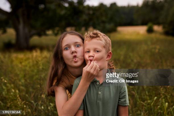 playful boy and girl pulling faces in nature - portrait grimace photos et images de collection