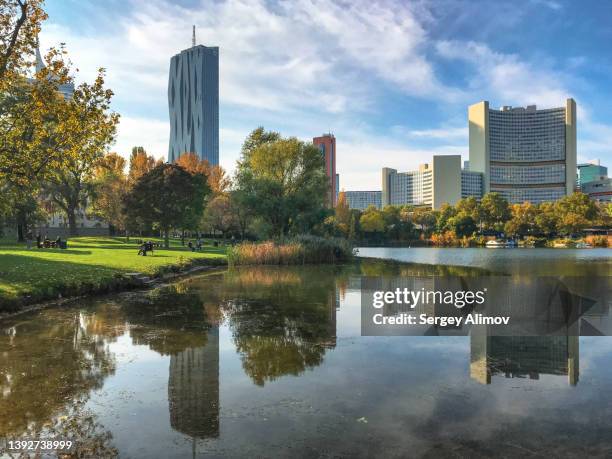 reflection of buildings in lake of public park - österreich durchblick stock-fotos und bilder