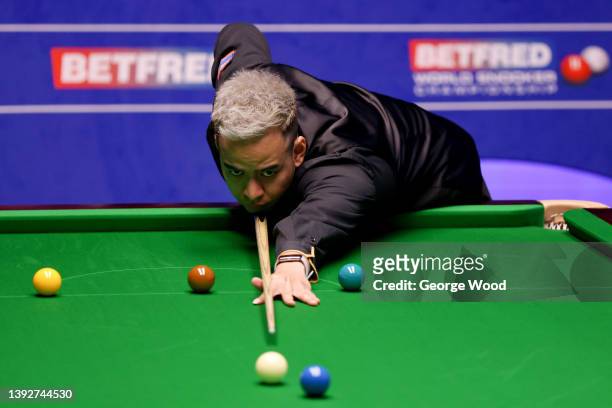 Noppon Saengkham of Thailand plays a shot during the Betfred World Snooker Championship Round One match between Luca Brecel of Belgium and Noppon...