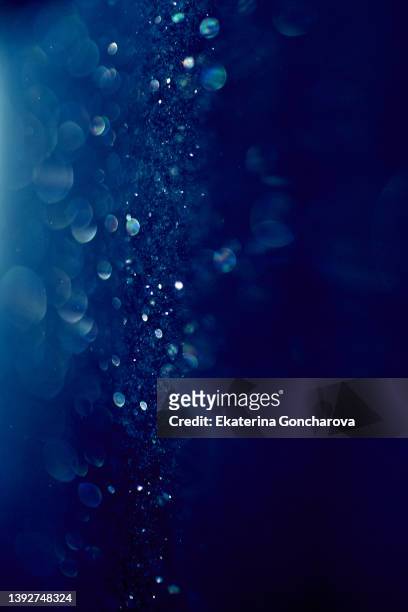 beautiful magical blue background with small round dust particles sparkling in the rays of light - royal blue imagens e fotografias de stock