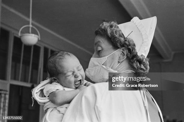 Midwife holds a newborn baby in the maternity unit of a hospital, UK, 1956. Original Publication: Picture Post - 9111 - Analgesia - unpub.