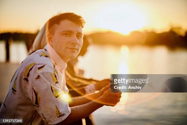 porträt eines lächelnden jungen transgender-mannes, der mit seinen freunden den sonnenuntergang beobachtet - ftm stock-fotos und bilder