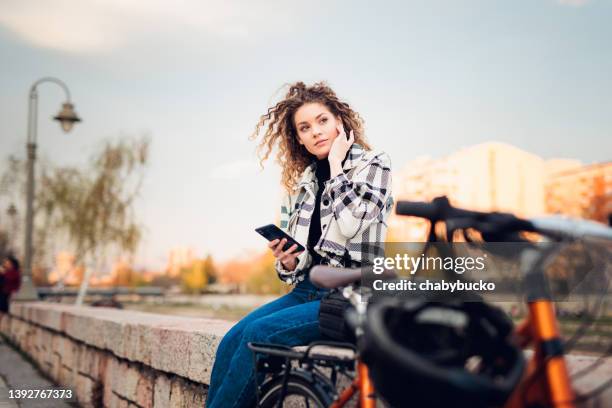 mujer que viaja en bicicleta esperando la llamada - business smartphone happy spring fotografías e imágenes de stock