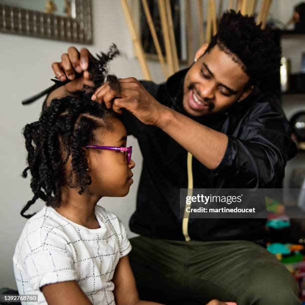 father undoing braids of young daughter in living room. - braided hair stock pictures, royalty-free photos & images