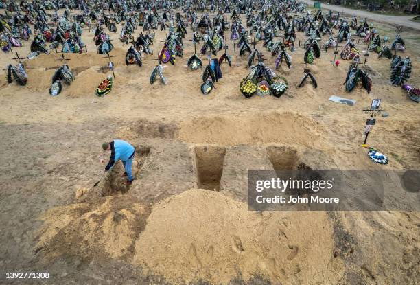 In this drone image, A grave digger prepares the ground for a funeral at a cemetery on April 21, 2022 in Irpin, Ukraine. The first several rows...