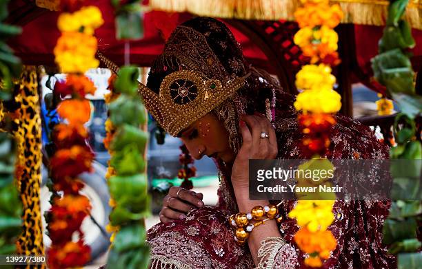 Hindu woman dressed as Goddess Parvati sits in palanquin as she participates in Hindu religious procession on the eve of Shivratri festival which...