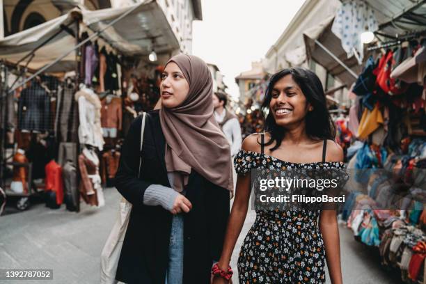 two friends are walking in san lorenzo market in florence, italy - gen z shopping stock pictures, royalty-free photos & images