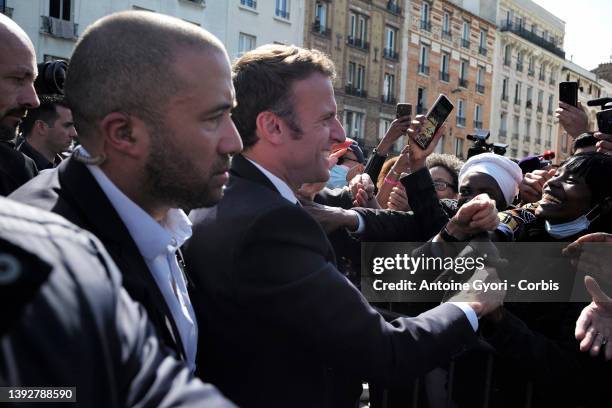 French President and La Republique en Marche party candidate for re-election Emmanuel Macron holds hands of inhabitants during a campaign visit in...