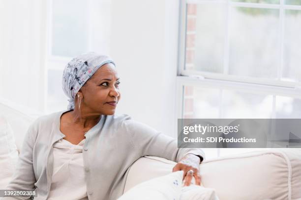 calm, peaceful senior female cancer patient looks out window - geduld stockfoto's en -beelden