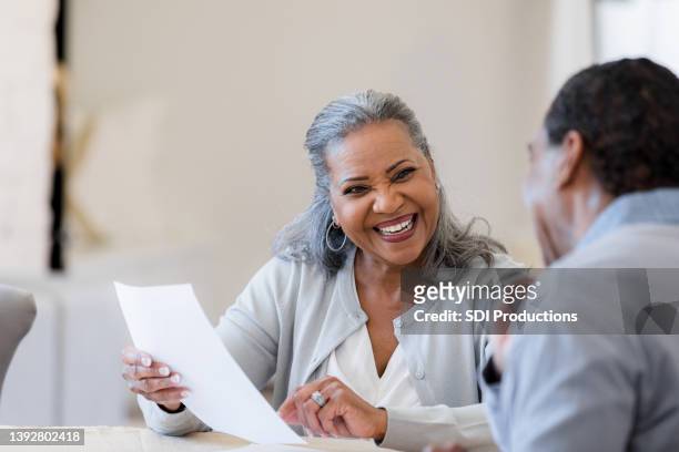 senior wife smiles happily at unrecognizable husband - lawyer explaining stock pictures, royalty-free photos & images