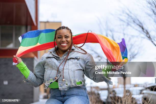 confident black woman outdoors holding a rainbow flag - rainbow flag stock pictures, royalty-free photos & images