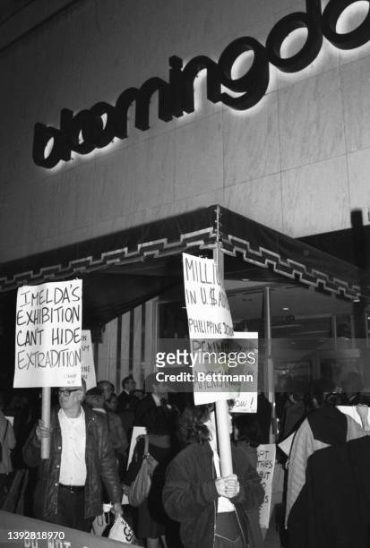 Carrying signs, protestors march outside Bloomingdale's department store. Inside, Imelda Marcos, First Lady of the Philippines, was visiting a...