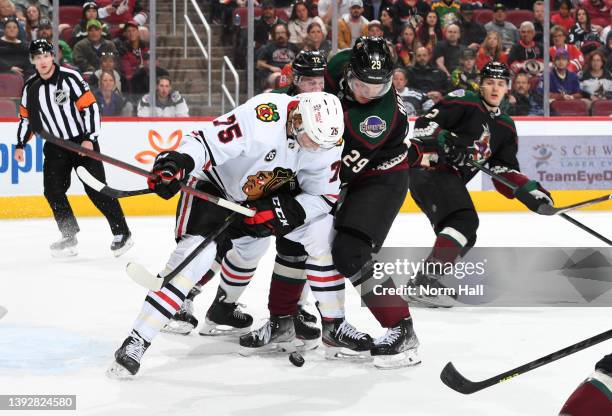 Alec Regula of the Chicago Blackhawks battles for a loose puck with Barrett Hayton of the Arizona Coyotes at Gila River Arena on April 20, 2022 in...