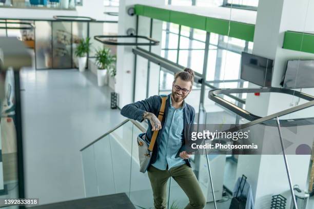 young man arriving at work - man bun stock pictures, royalty-free photos & images