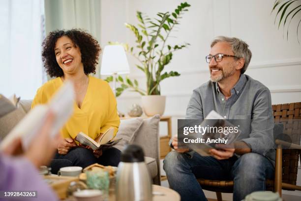 mature adult man enjoying book club - friends talking living room stock pictures, royalty-free photos & images