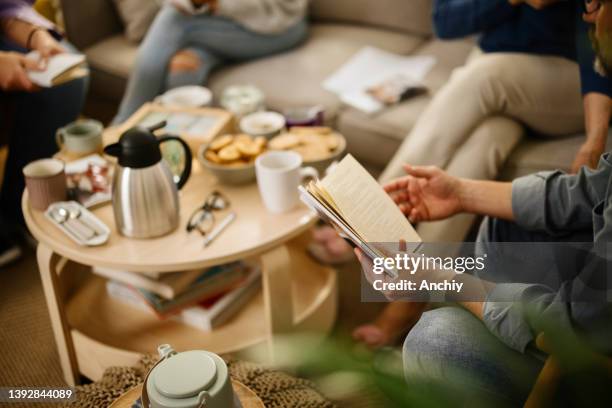 over the shoulder view of a unrecognisable man's hand following the lines of text in a book. - poetry stock pictures, royalty-free photos & images