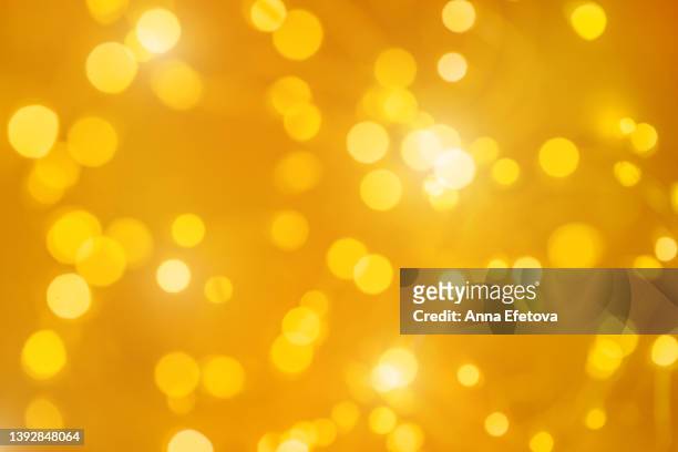 festive gold christmas background made of glowing defocused garland with many lights. concept of new year celebration - winter and warm glow stock-fotos und bilder
