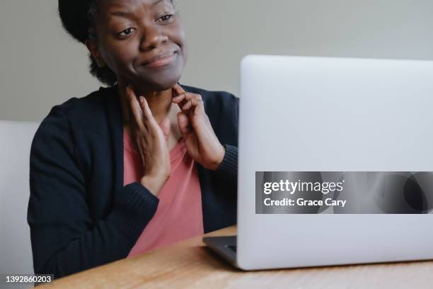 woman feels swollen glands in neck while consulting with doctor online - lymphatic system stock pictures, royalty-free photos & images