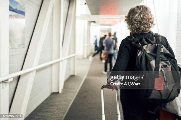 mature woman waiting in line to board a flight - passenger boarding bridge stock pictures, royalty-free photos & images