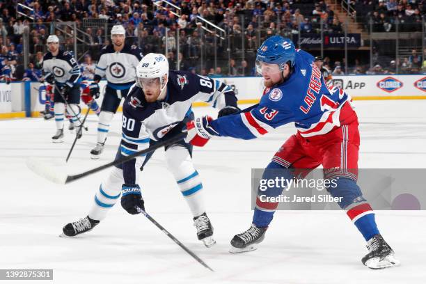 Alexis Lafreniere of the New York Rangers skates against Pierre-Luc Dubois of the Winnipeg Jets at Madison Square Garden on April 19, 2022 in New...