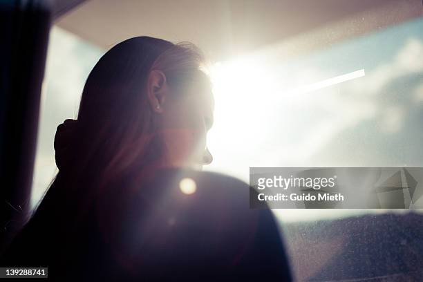 women looking out window in back light. - woman looking out window stockfoto's en -beelden
