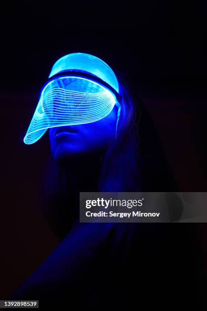 dark portrait of woman with technology beauty mask - futuristic chair photos et images de collection