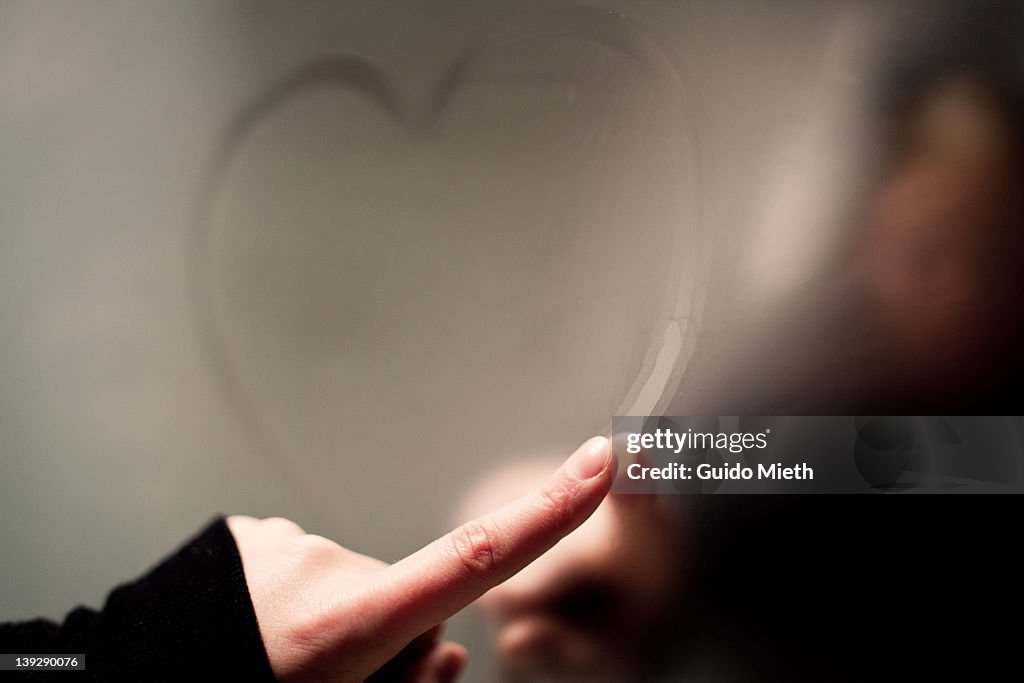 Writing heart on steamy mirror