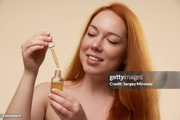 ginger woman with face serum - applying oil stock pictures, royalty-free photos & images