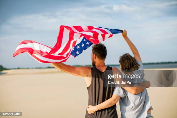 couple with american flag at the beach celebrating independence day - american flag ocean 個照片及圖片檔