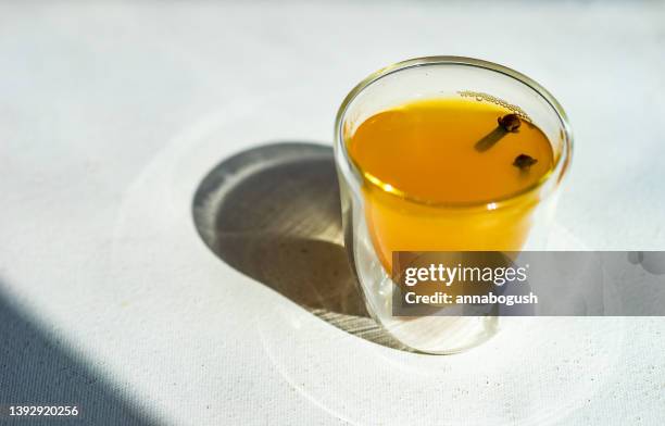 shot of turmeric moon milk with fresh cloves - ginger glasses stock-fotos und bilder