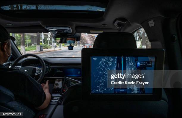 Monitor shows the real-time location of the vehicle as a "safety driver" sits with his hands off the wheel in an Apollo Moon robotaxi on the road as...