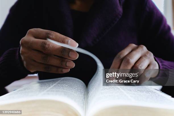 woman reading bible turns page - religious equipment fotografías e imágenes de stock