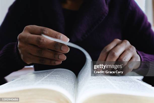 woman reading bible turns page - objet de culte photos et images de collection