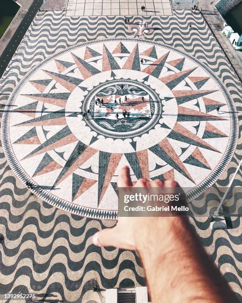 hand of man pointing huge compass rose in lisbon with world map showing portuguese discoveries - mapa portugal imagens e fotografias de stock