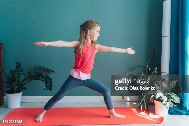 concentrated cute little girl doing sport yoga exercises, holding arms up and spreading legs - barefoot girl stock pictures, royalty-free photos & images