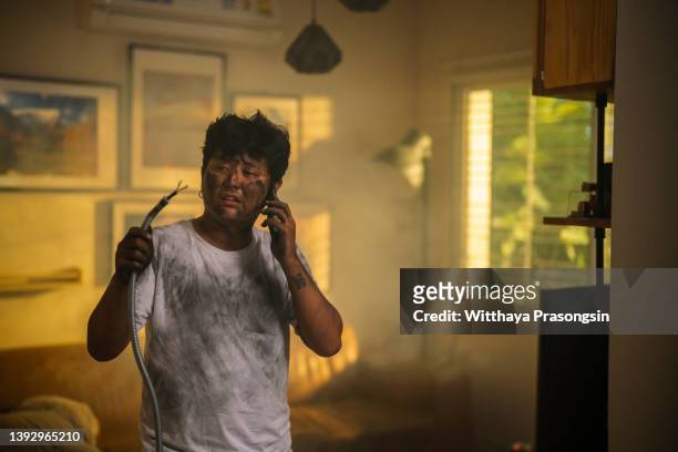 young man holding electrical cable smoking after electrical accident with dirty burnt face in funny desperate - man electric chair stock pictures, royalty-free photos & images