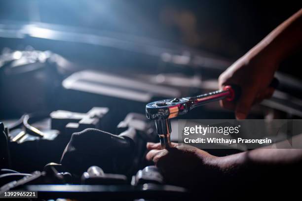 auto mechanic working on car engine in mechanics garage. repair service. authentic close-up shot - maquinaria fotografías e imágenes de stock