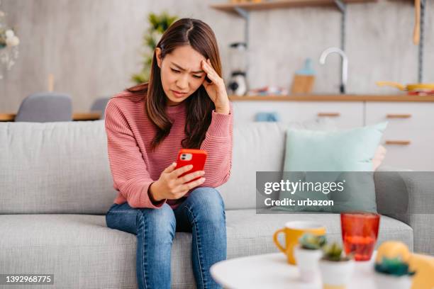 young woman receiving a sad text message - receiving text stock pictures, royalty-free photos & images