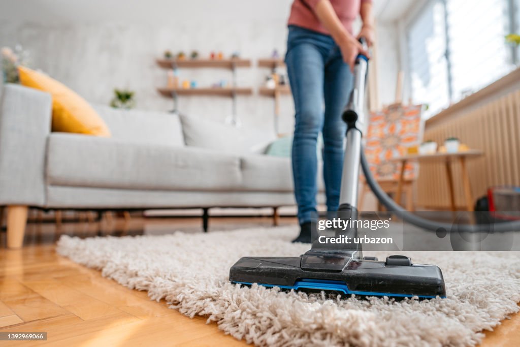 Mujer joven aspirando su apartamento
