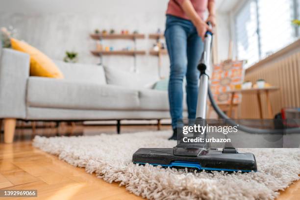 mujer joven aspirando su apartamento - aspirador fotografías e imágenes de stock