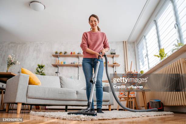 young woman vacuuming her apartment - vacuum cleaner woman stock pictures, royalty-free photos & images