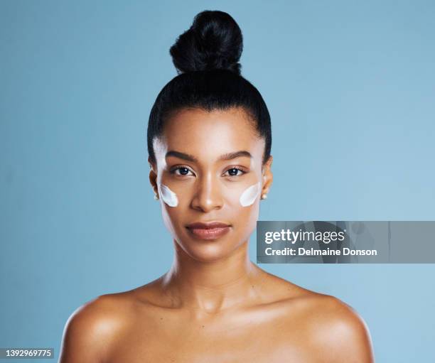 studio shot of a young woman applying lotion against a blue background - beautiful naked female body front view stock pictures, royalty-free photos & images