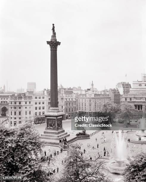 1950s 1960s Lord Nelson's Column People Pedestrians Walking About Trafalgar Square Central London City Of Westminster England Uk.