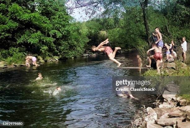 1950s Summer Fun Group Of Boys And Girls Swimming And Diving In Creek Stream Pond Old Swimming Hole.